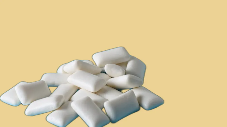 Pile of white chewing gum pellets on a pale yellow background
