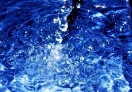 Close-up of clear water splashing with bubbles against a blue background