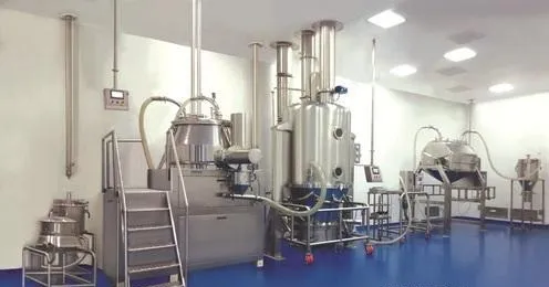 Stainless steel granulation equipment, including a mixer granulator and a fluid bed dryer, in a clean processing room with a blue floor