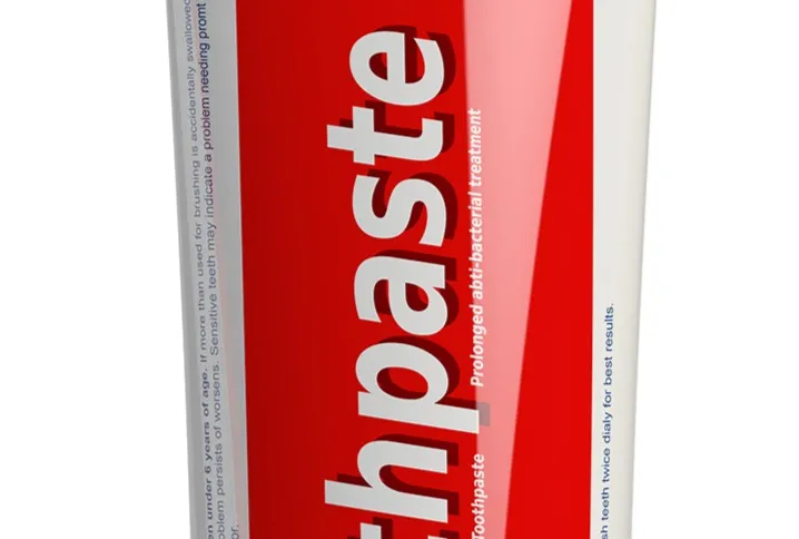 White and red 100 g toothpaste tube standing upright on its cap against a white background